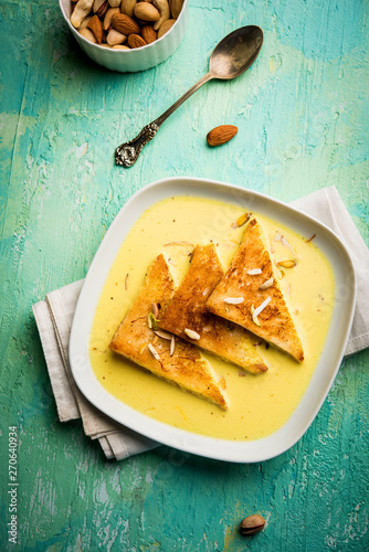 shahi tukra/tukda or Double ka meetha is a bread pudding Indian sweet of fried bread slices soaked in rabid or sweet saffron milk garnished with dry fruits, selective focus photo