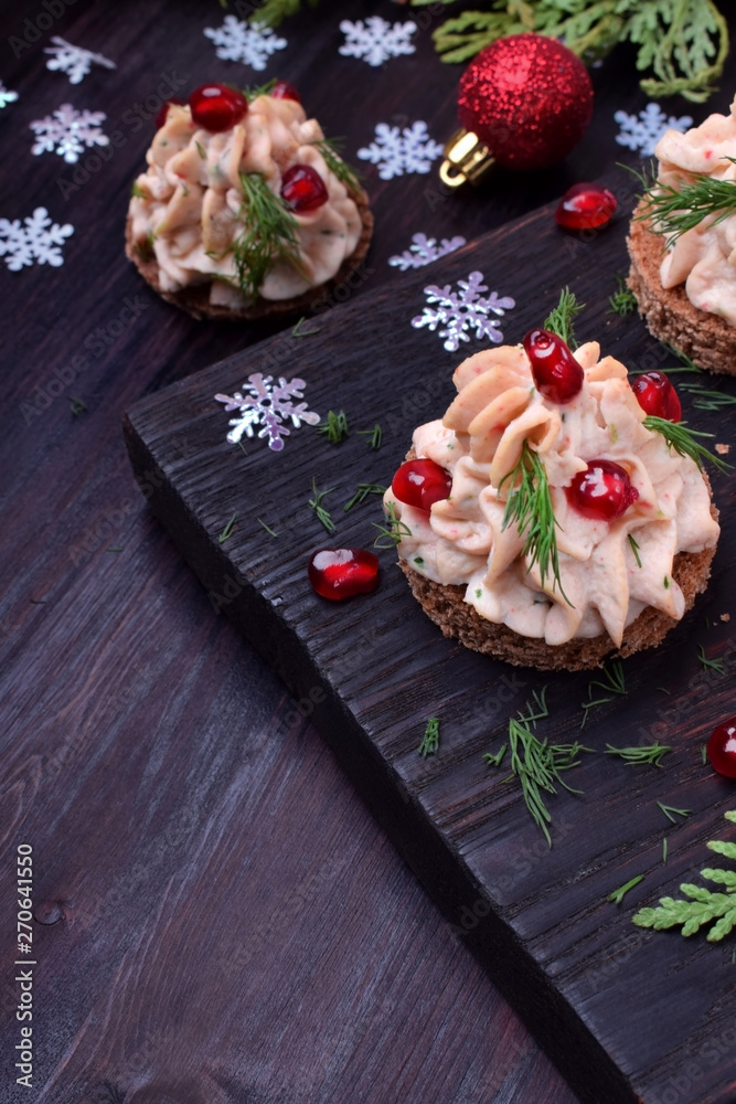 Canape shaped as a Christmas tree with pate garnished with pomegranate and dill surrounded by Christmas decorations Canape shaped as a Christmas tree with pate garnished with pomegranate and dill surrounded by Christmas decorations