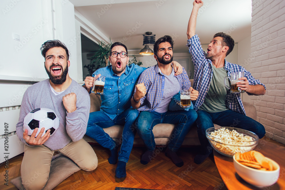 Men watching sport on tv together at home screaming cheerful. Group of friends sitting on the couch and watching a football game. Men watching sport on tv together at home screaming cheerful. Group of friends sitting on the couch and watching a football game.