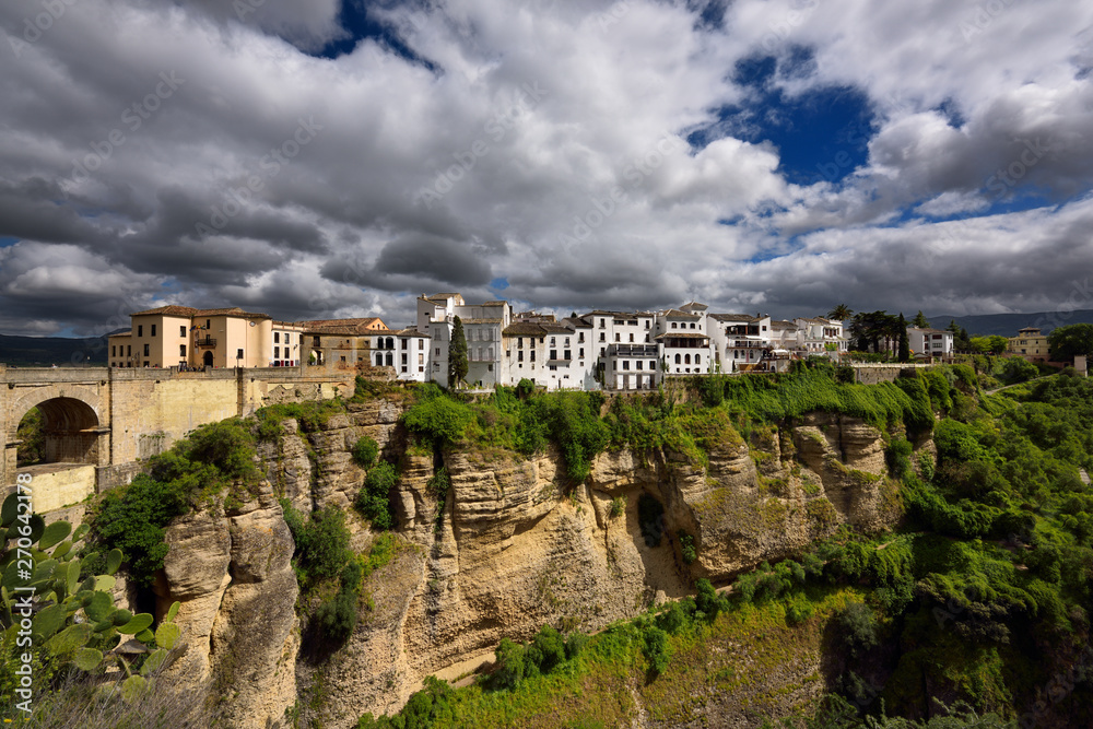 Fototapeta premium Sun on white buildings and orange cliffs at El Tajo Gorge Ronda Spain