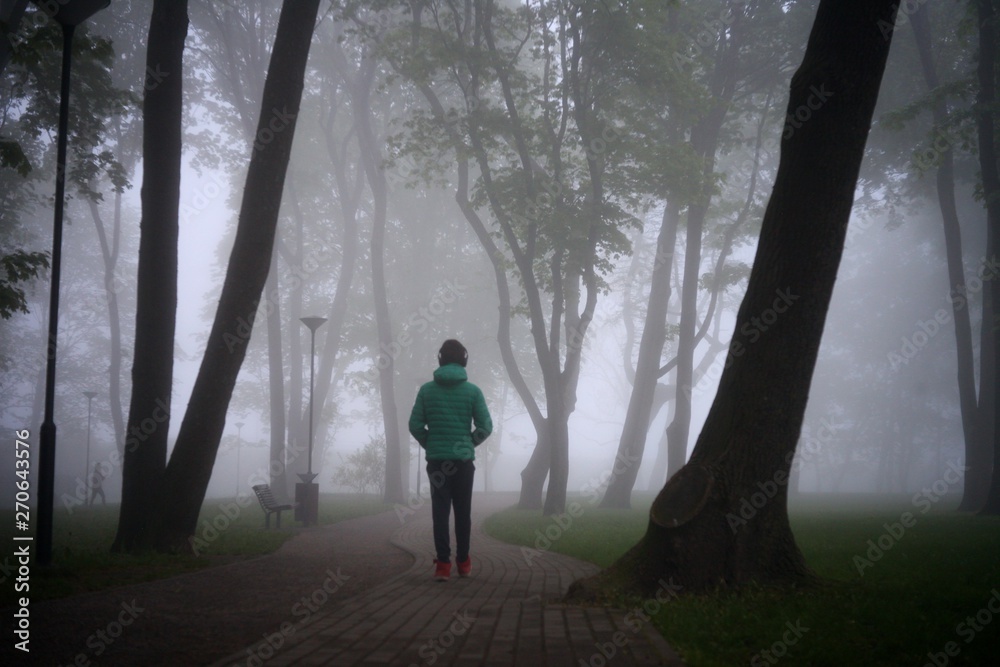 city park in foggy day - person at the foggy park. Loneliness concept.