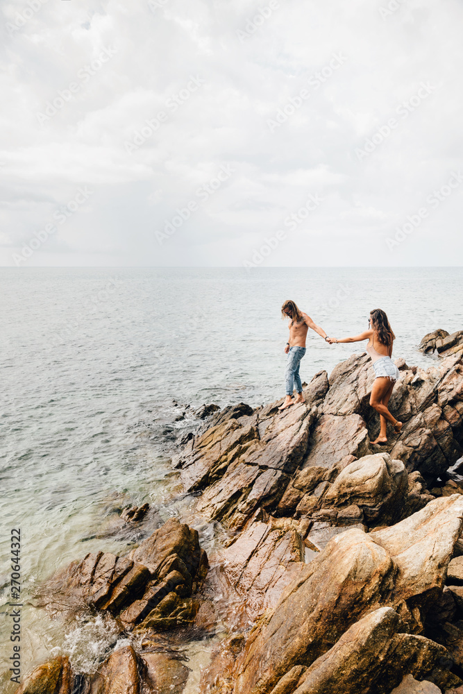 Beautiful couple climbing the rocks on the beach Beautiful couple climbing the rocks on the beach