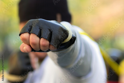 Boxer man strikes with his fist in a protective glove at the target. In his fist clamped with great rubber from the trainer.