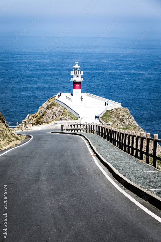 lighthouse on road coast of sea