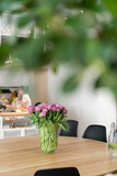A large bouquet of pink tulips in a glass vase adorns the interior in a cafe or restaurant.