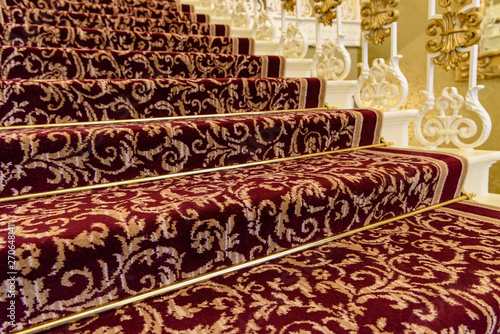 Brass stairrods holding down red patterened Axminster carpet on the stairs of a posh house. photo