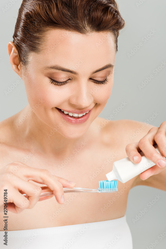 cheerful woman holding toothpaste near toothbrush isolated on grey cheerful woman holding toothpaste near toothbrush isolated on grey