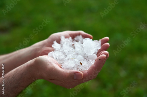 large pieces of ice hail in the palm of your hand. man holding a handful of large hailstones. consequences of natural anomalies.