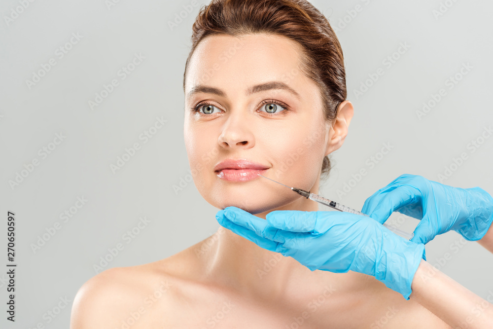 cropped view of cosmetologist in blue latex gloves holding syringe near face of naked woman isolated on grey cropped view of cosmetologist in blue latex gloves holding syringe near face of naked woman isolated on grey