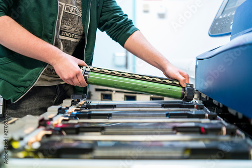 Close-up of teenager working at color printer inserting print cartridge photo