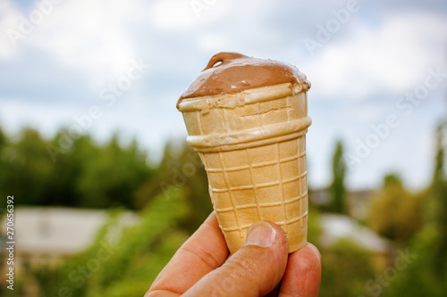 Hand holding ice cream on blurred natural background photo