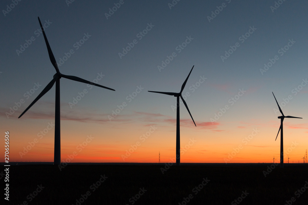 A landscape with windmills in a wind farm at sunset. A landscape with windmills in a wind farm at sunset.