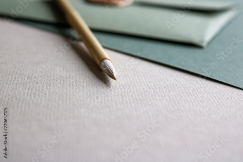 Close up of green coloured fine art paper, a green envelope with a golden seal and a wooden calligraphy brush laying on top of it photo