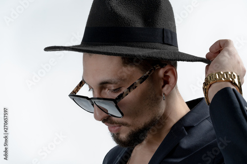 Close up portrait of young bearded serious man in black suit and hat isaolated over white background photo