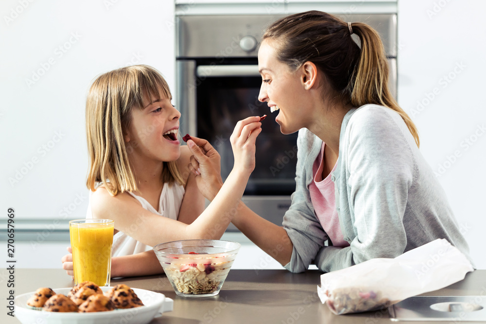 Beautiful mother and daughter feeding cereals to each other at home. Beautiful mother and daughter feeding cereals to each other at home.