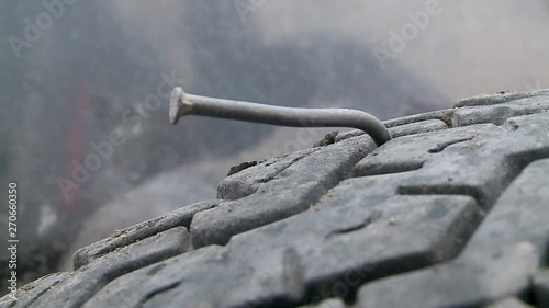 An extreme close up shot of a bent metallic  nail on a tyre