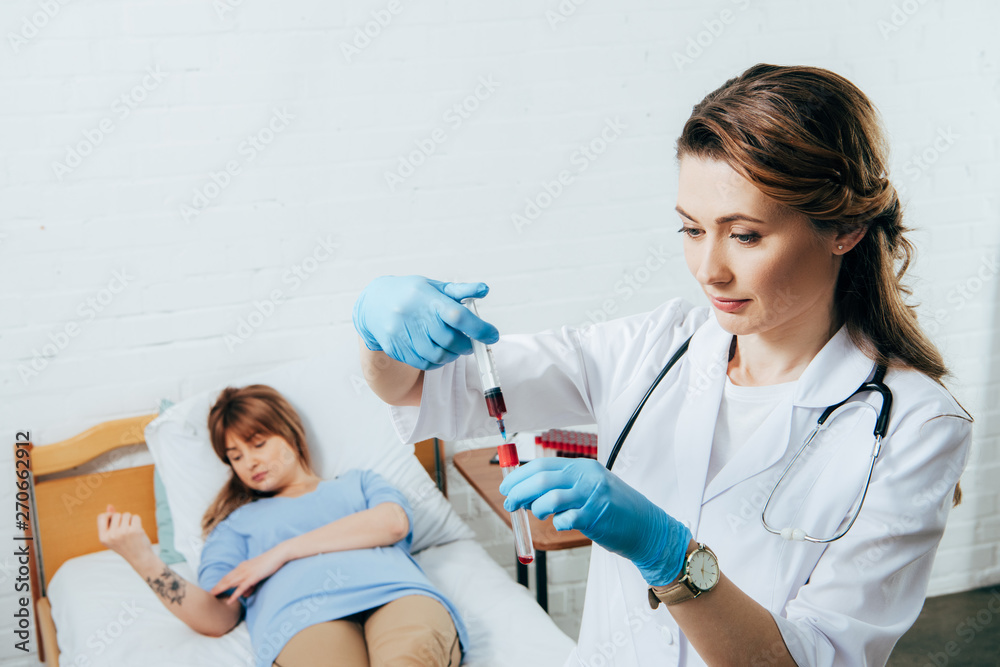 donor on bed and doctor holding syringe with blood sample and test tube donor on bed and doctor holding syringe with blood sample and test tube