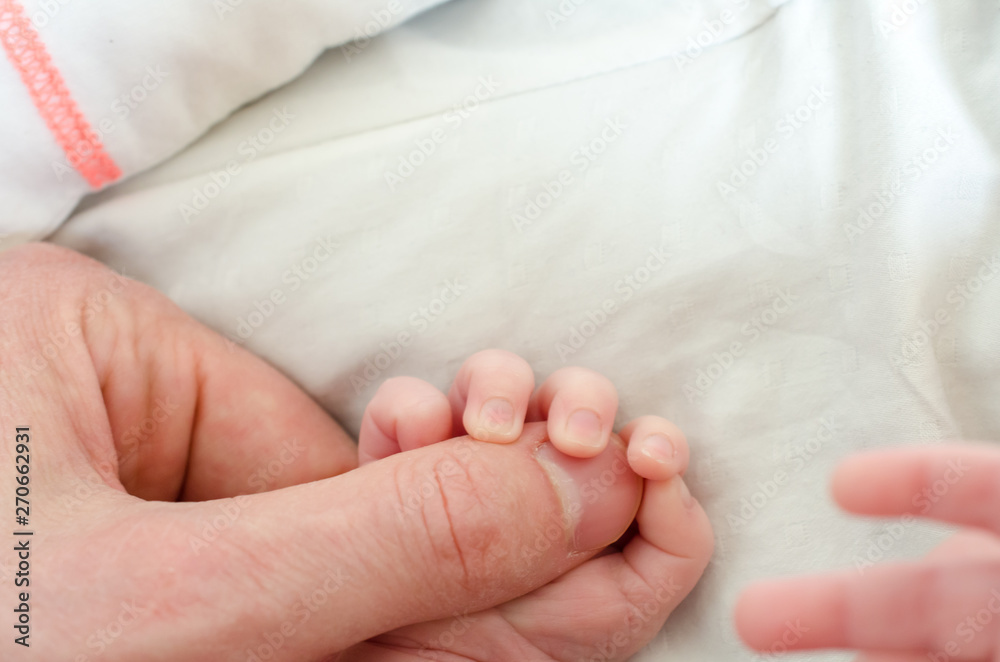 Hand of newborn baby holding male adults finger. Concept of help and family. Father holding hand. Hand of newborn baby holding male adults finger. Concept of help and family. Father holding hand.