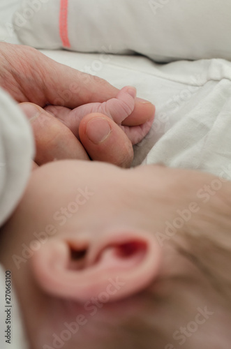 Hand of newborn baby holding male adults finger. Concept of help and family. Father holding hand.