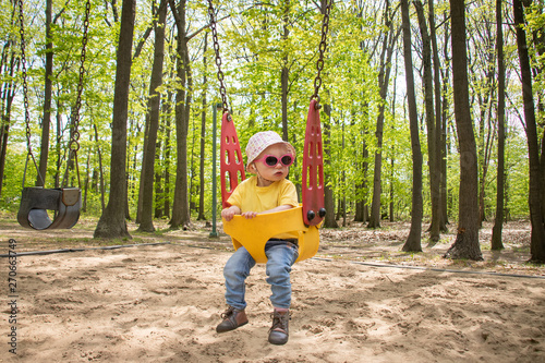 adorable blond caucasian toddler in the swing at the playground © juliedeshaies