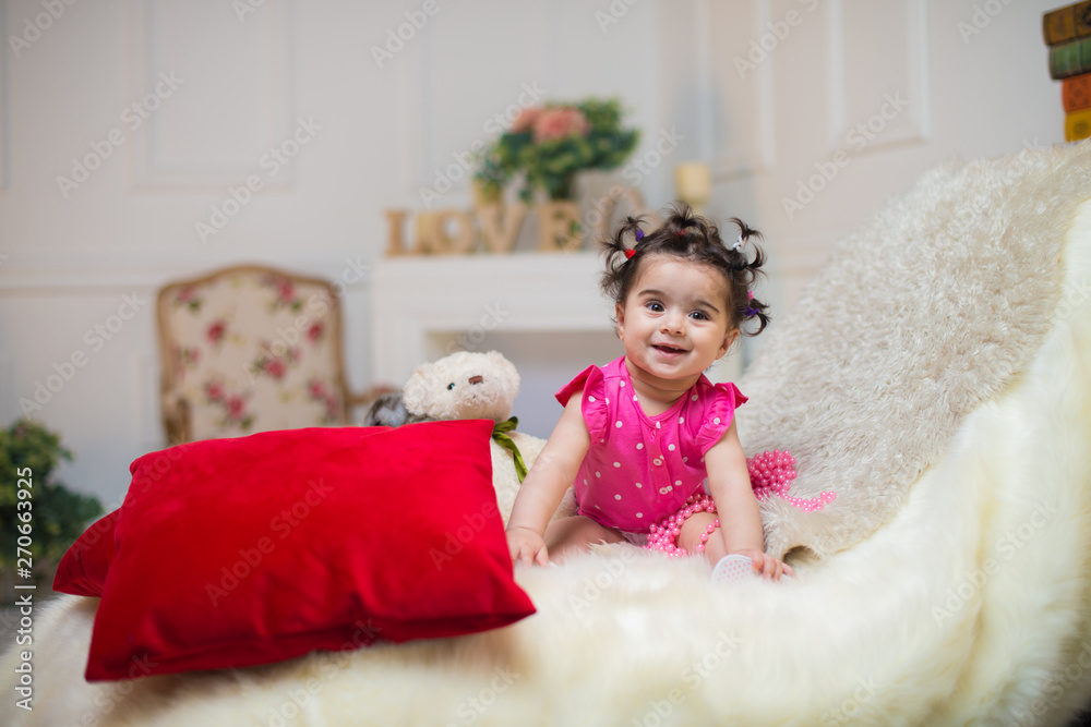 Happy smiling sweet baby girl sitting on sofa with bear toy