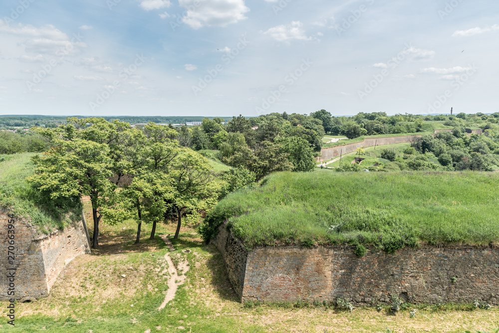 Remains of old fortress with brick walls protective trenches as fortification obstacles and grass