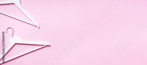 Top view of white clothes hangers on pink background with copy space. Flat lay. Minimalism style. Creative layout. Fashion, store sale, shopping concept. Banner for feminine blog
