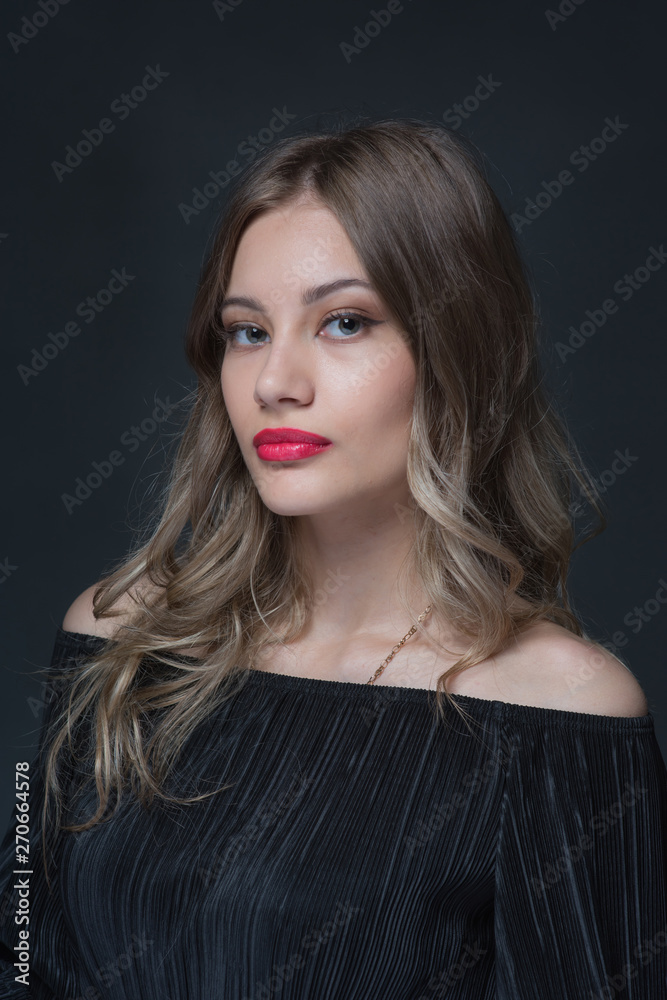 Beautiful ,young blonde with bright red lips and expressive eyes in a black jumpsuit. Beauty portrait of a girl. Emotional and bright appearance. Fashion portrait of a woman.