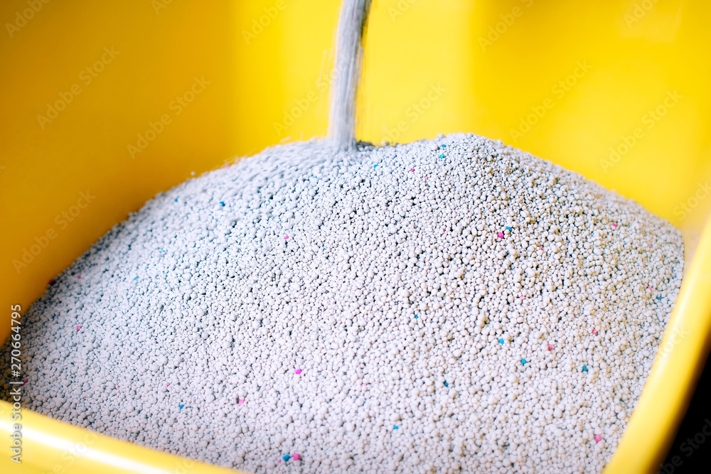 Fresh Cat Sand Pouring into a Yellow Litter Box. Stock Photo Adobe Stock