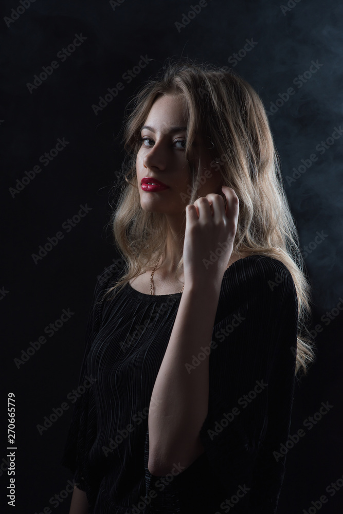Fototapeta premium Beautiful ,young blonde with bright red lips and expressive eyes in a black jumpsuit. Beauty portrait of a girl. Emotional and bright appearance. Fashion portrait of a woman.
