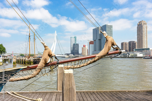 View through the ship's ropes and the bowsprit of a sailing ship on the imposing buildings at the Erasmus bridge