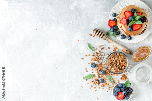 Healthy breakfast with american pancake, granola, fruits, berries on white background.
