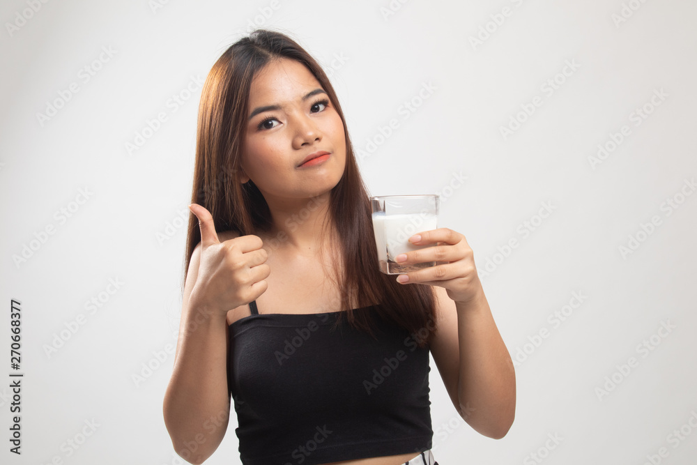 Healthy Asian woman drinking a glass of milk thumbs up. Healthy Asian woman drinking a glass of milk thumbs up.