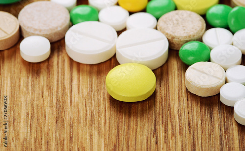 Stack of different pills isolated on wooden background