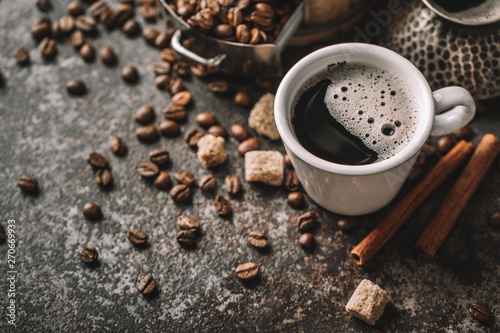 Coffee cup and coffee beans on dark stone background.