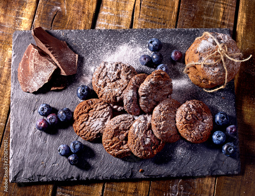 Serving food on slate onto wooden table. Oatmeal cookies biscuit with blueberry on picnic dark tiles countrylike. Chocolate chip cookies tied with string. High carbohydrate content.