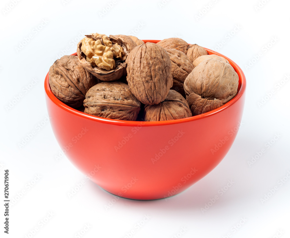 pile of walnuts lying in an orange bowl on a white background pile of walnuts lying in an orange bowl on a white background
