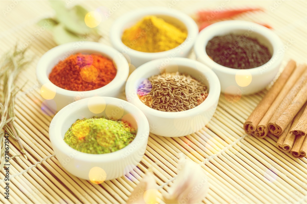 Various colorful spices in bowls on wooden table