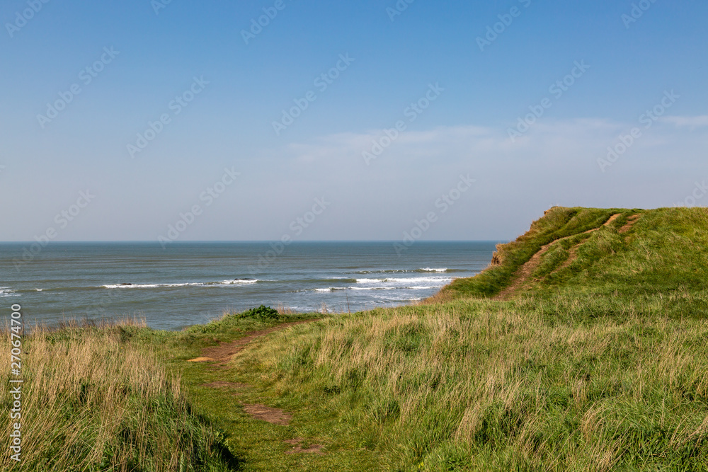 Looking out over grass covered cliffs towards the ocean, on the Isle of Wight coast