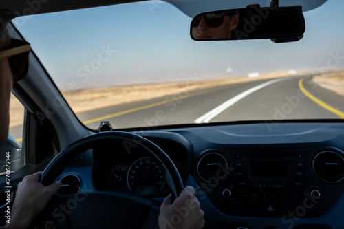 young man driving a rented car in the desert