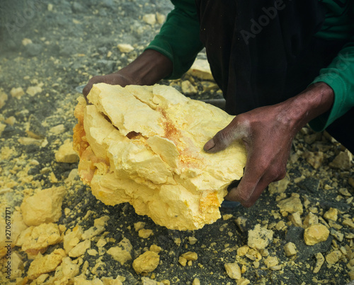 Hands with big yellow stone of sulfur photo