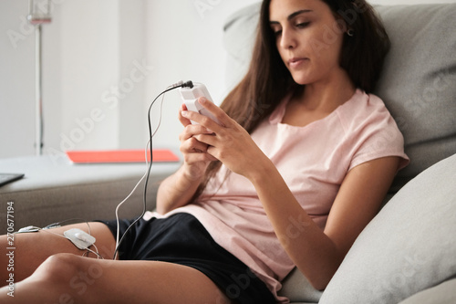 Woman Using Electrostimulator On Sofa photo