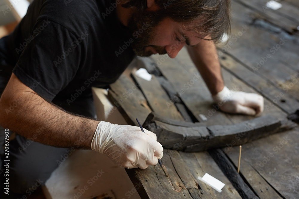 Man working with the restoration of an old boat in a museum Man working with the restoration of an old boat in a museum