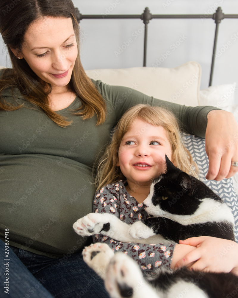 beautiful pregnant mother with her daughter who is holding her cat. beautiful pregnant mother with her daughter who is holding her cat.
