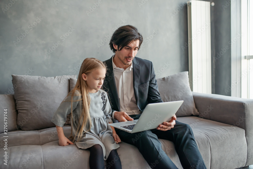 Happy little girl watching a movie on the computer with her father Happy little girl watching a movie on the computer with her father