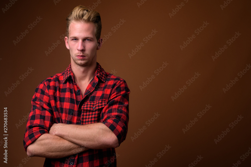 Fototapeta premium Studio shot of young handsome man against brown background