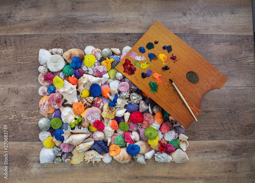 Painted sea shells. Collection of shells painted in different colors. Color pallet with paint brush