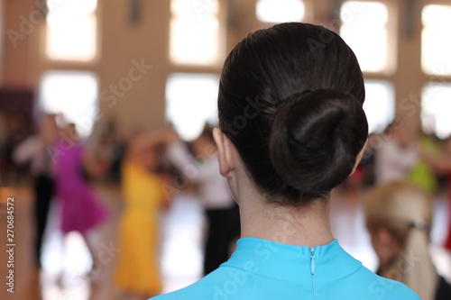 The head of a girl with a ballroom hairstyle on the background of dancing couples at the ballroom dancing tournament.