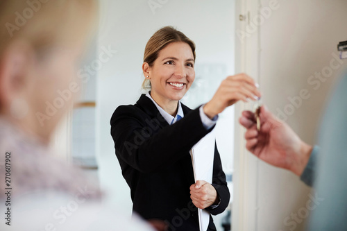 Confident smiling realtor giving house keys to couple