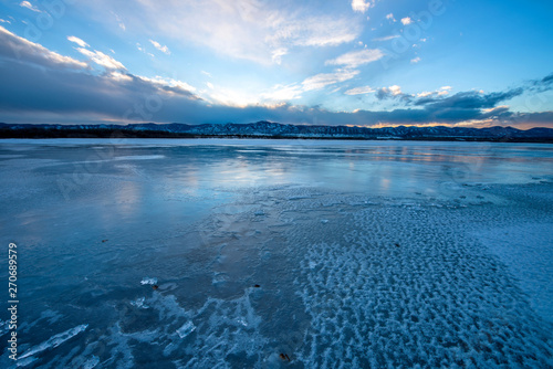 Sunset Stormy Icy Lake - Sunset at a frozen solid mountain lake as a winter storm moving in. Chatfield State Park, Denver-Littleton, Colorado, USA. photo